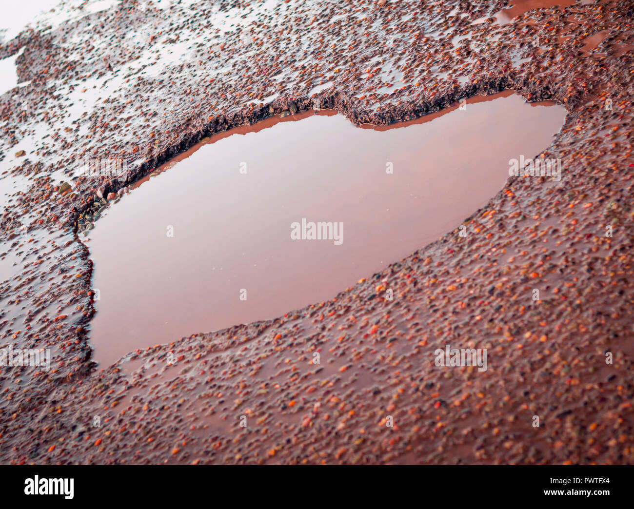 Herzförmige Schlagloch In der Alten Asphaltstraße mit Pfützen, Kies, Steine. Liebe Zeichen Stockfoto