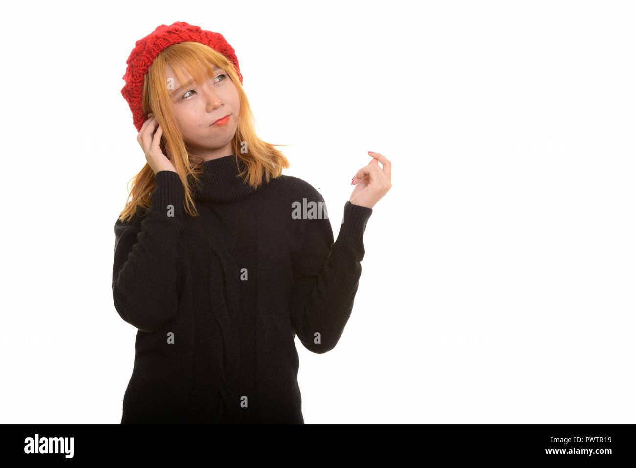 Junge süße nachdenkliche asiatische Frau mit Hut beim Denken Stockfoto