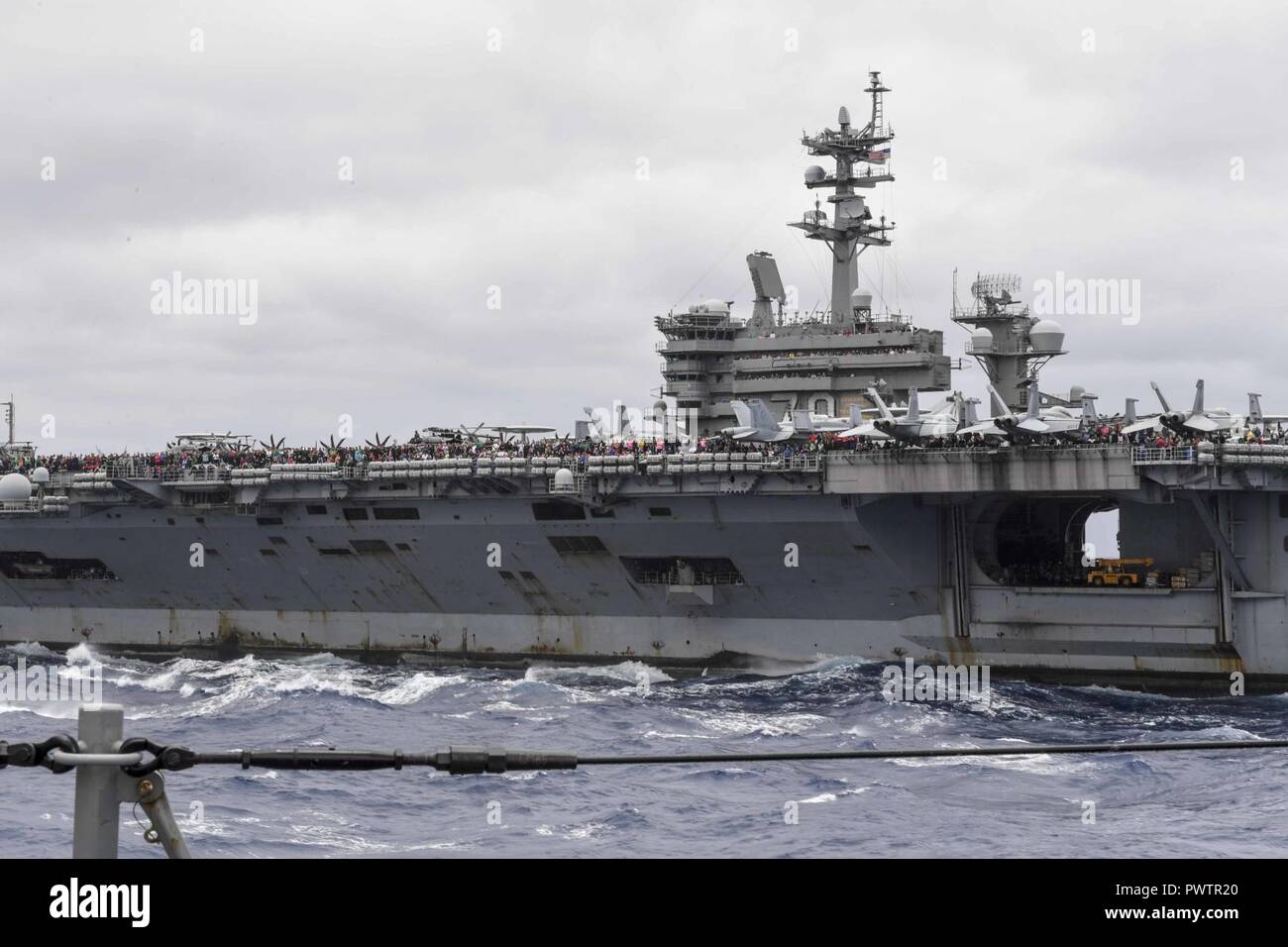 Pazifik (19. Juni 2017) Freunde und Familie der Mitglieder der Besatzung an Bord der Nimitz-Klasse Flugzeugträger USS Carl Vinson (CVN 70) versammeln sich auf dem Flugdeck der Arleigh-Burke-Klasse geführte Anti-raketen-Zerstörer USS Wayne E.Meyer (DDG108) schießen ein Schließen - in Waffen System (Ciws) für ein Sea Power Demonstration während einer Tiger Cruise. Die US-Marine hat die Indo-Asia - Pazifik routinemäßig für mehr als 70 Jahre patrouillierten die Förderung von Frieden und Sicherheit in der Region. ( Stockfoto