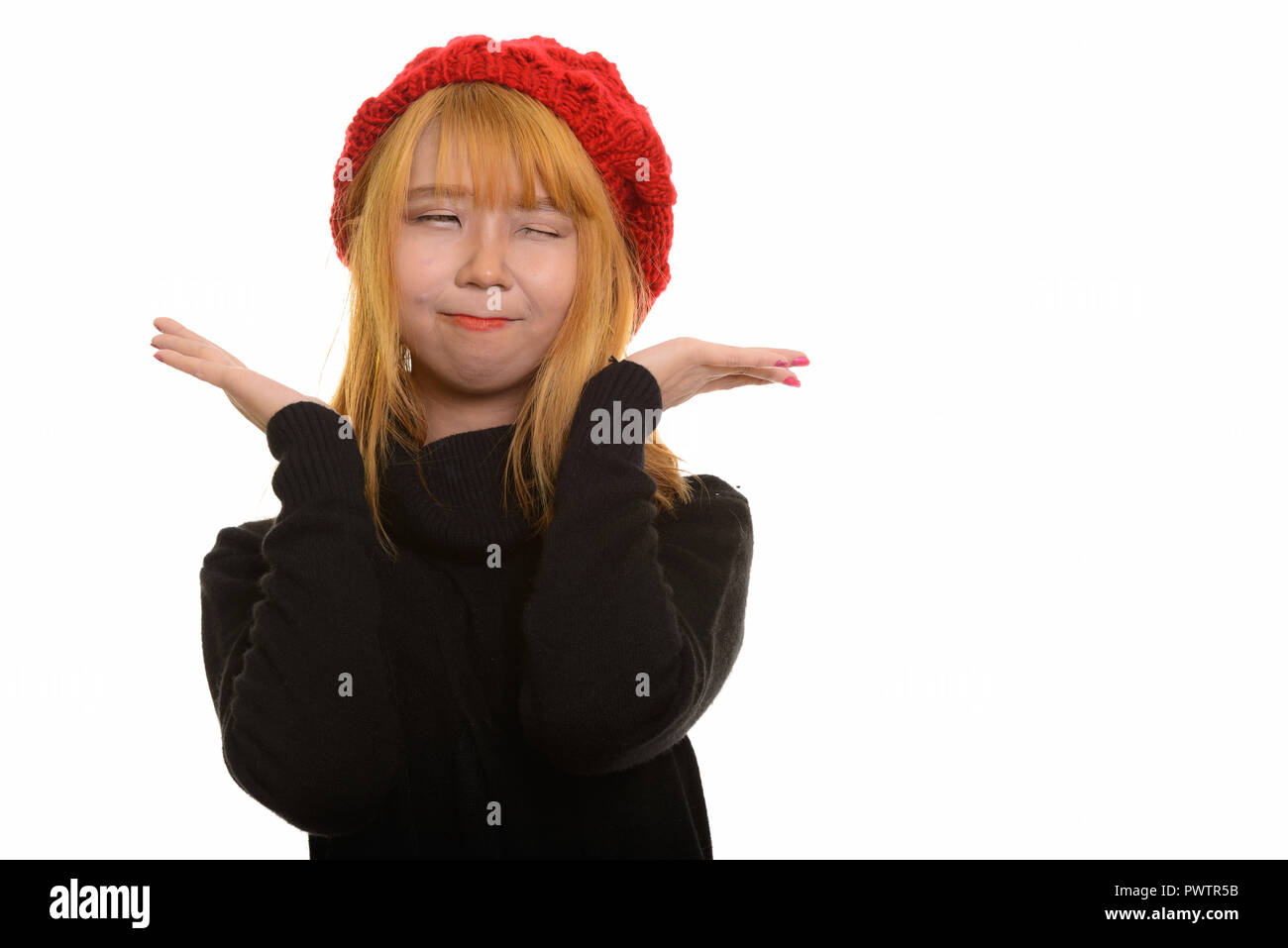 Junge süße asiatische Frau posiert mit den Händen in der Nähe des Gesichts- und winki Stockfoto