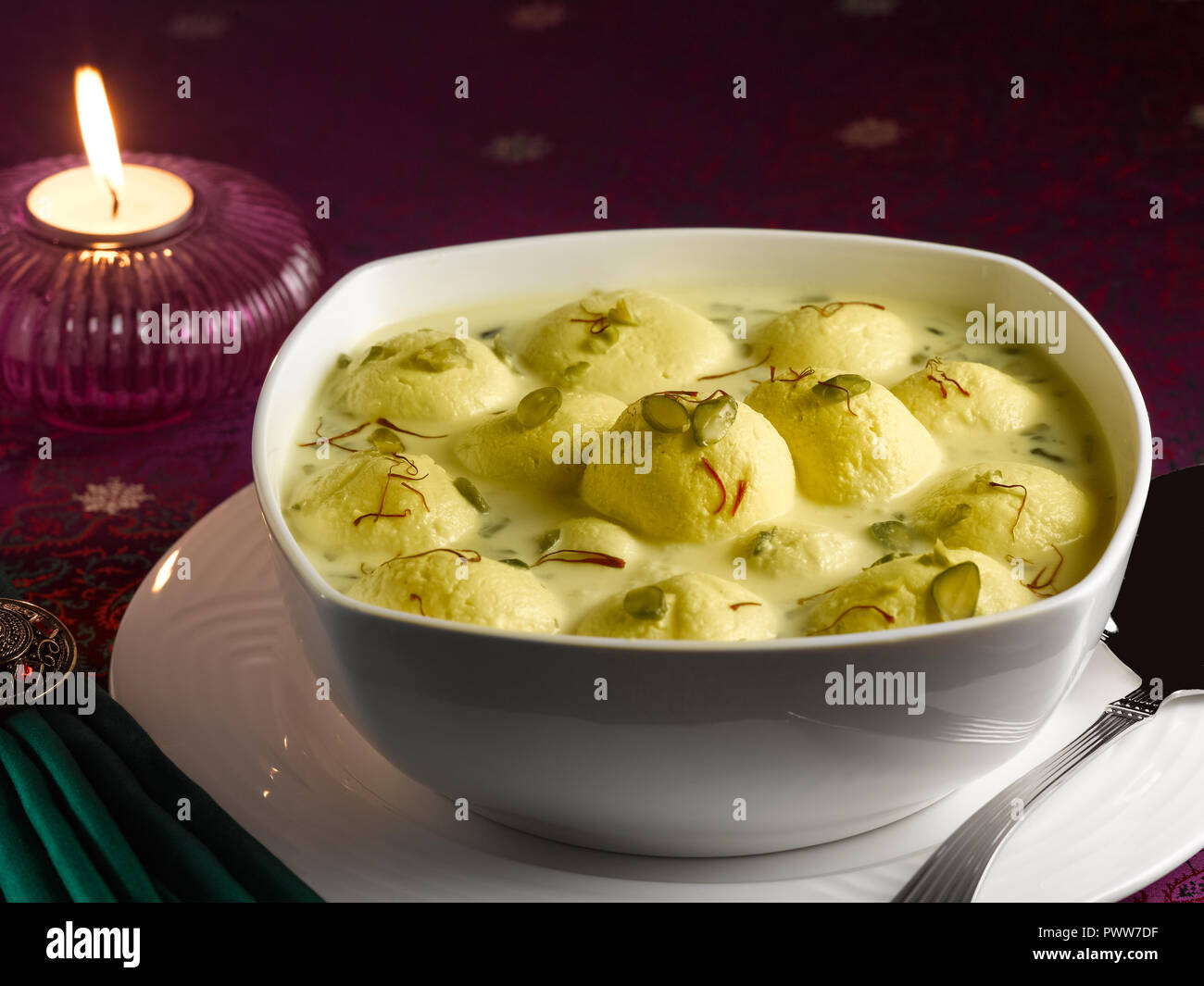 RASMALAI, ein indisches DESSERT AUS HÜTTENKÄSE GETRÄNKT IN SÜSSEN SAFRAN MILCH UND garniert mit Pistazien Stockfoto