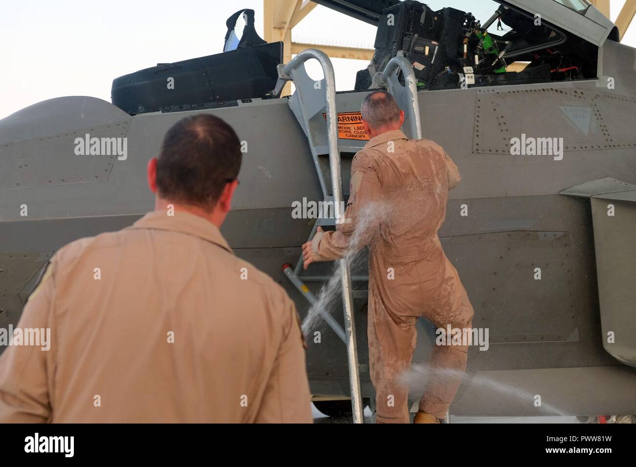 Brig. Gen. Charles S. Corcoran, 380 Air Expeditionary Wing Commander, klettert nach unten von einer F-22 Raptor, während mit Wasser an seinem Fini - Flug zum 30. Juni 2017 gesprüht wird, an einem geheimen Ort im Südwesten Asien. Nach seiner Amtszeit als 380 AEW-Commander, Corcoran ist geplant, die Position des stellvertretenden Stabschef für NATO-Operationen bei Allied Air Command Headquarters, Ramstein, Deutschland zu übernehmen. Stockfoto