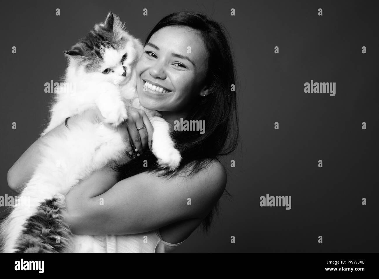 Junge asiatische Frau gegen grauen Hintergrund in Schwarz und Weiß Stockfoto