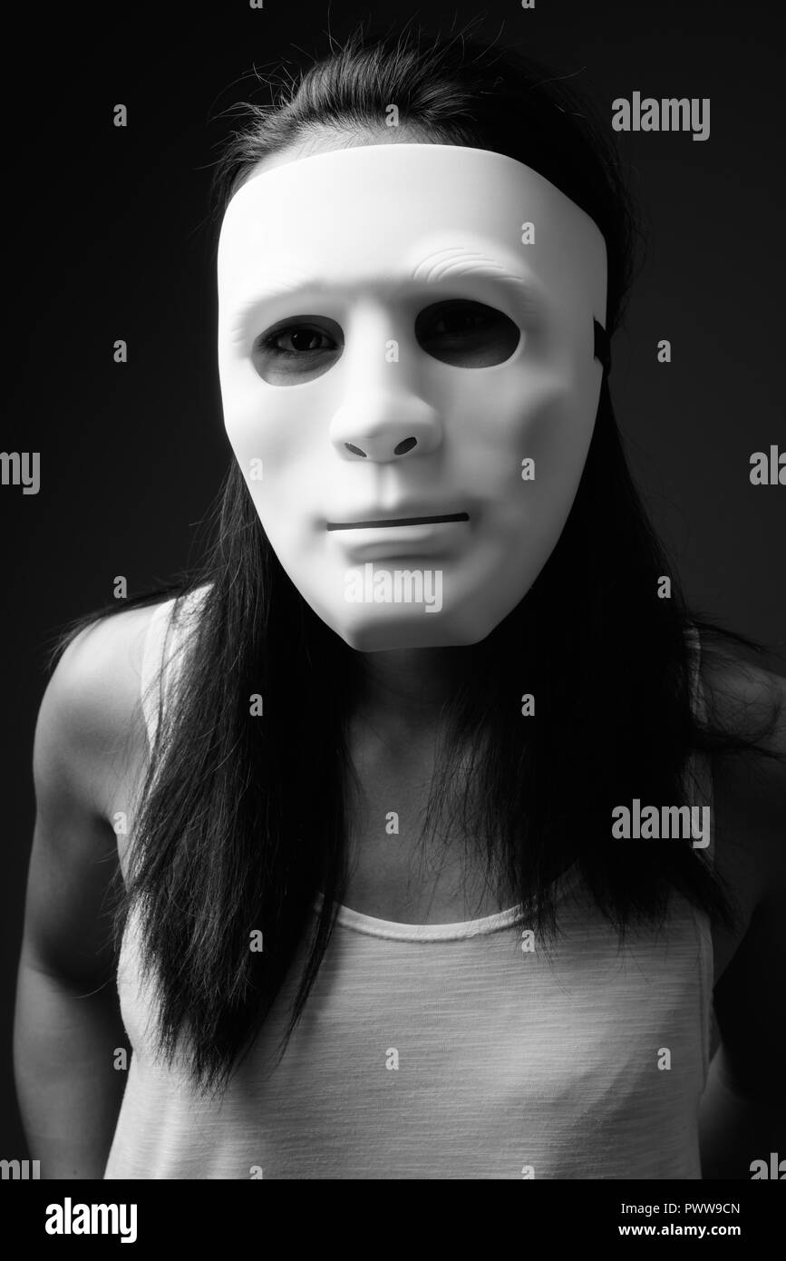 Junge asiatische Frau gegen grauen Hintergrund in Schwarz und Weiß Stockfoto