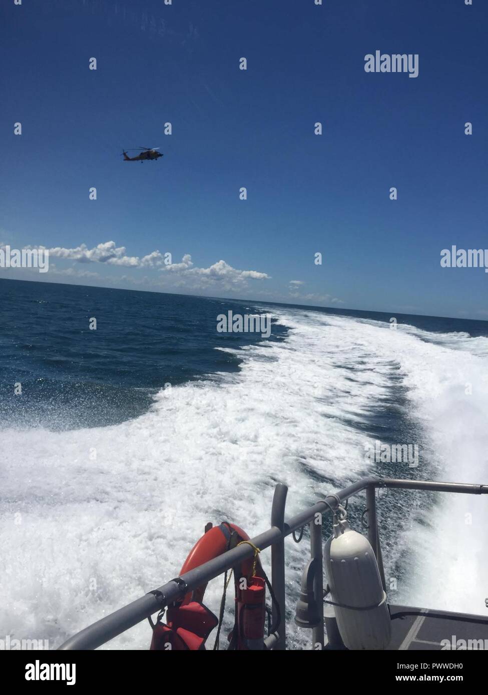 Ein 45-Fuß-Antwort Boat-Medium boatcrew von Station Sand Key und einem MH-60 Jayhawk Helikopter Crew von Air Station Clearwater reagieren zu acht Menschen an Bord eines 30-Fuß-charter Tauchboot nehmen auf Wasser 12 Meilen westlich von Anclote, Florida, Donnerstag, 6. Juli 2017. Die Jayhawk Crew und Besatzung koordiniert und entwässert die Charter Tauchboot Folge von Verletzungen. Stockfoto