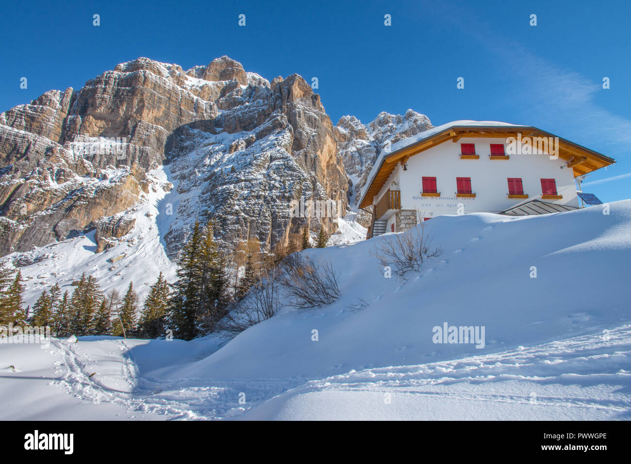 Bruto Carestiato Hütte, Berghütte in den italienischen Alpen. Wunderbar klaren Wintertag, Silvester auf dem Schnee. Imposante Berge, Pinienwald. Stockfoto