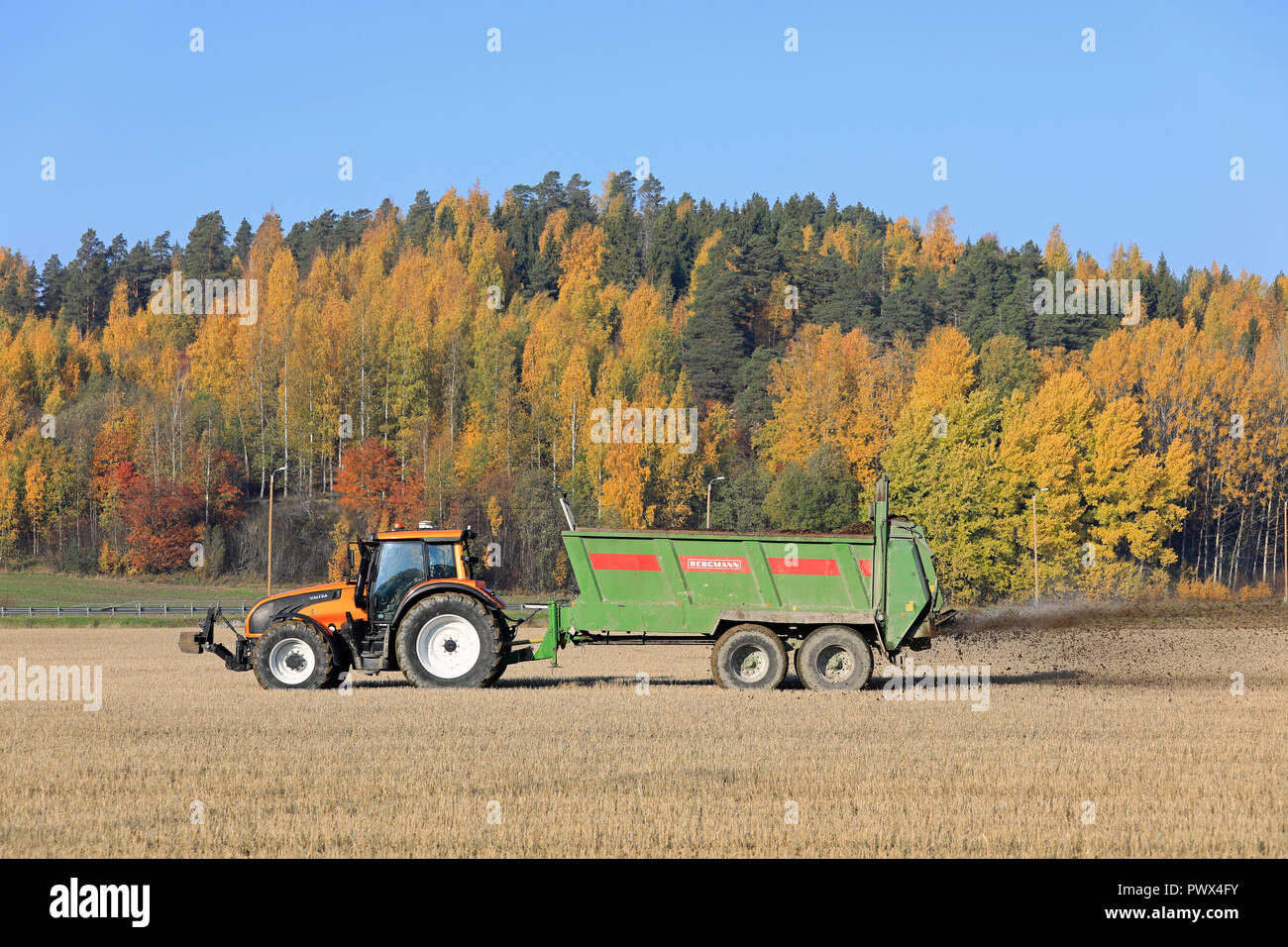 Salo, Finnland - Oktober 14, 2018: Landwirt Ausbringung von Gülle auf Stoppeln Feld mit Valtra Traktor und Bergmann Streuer an einem schönen Tag im Herbst. Stockfoto