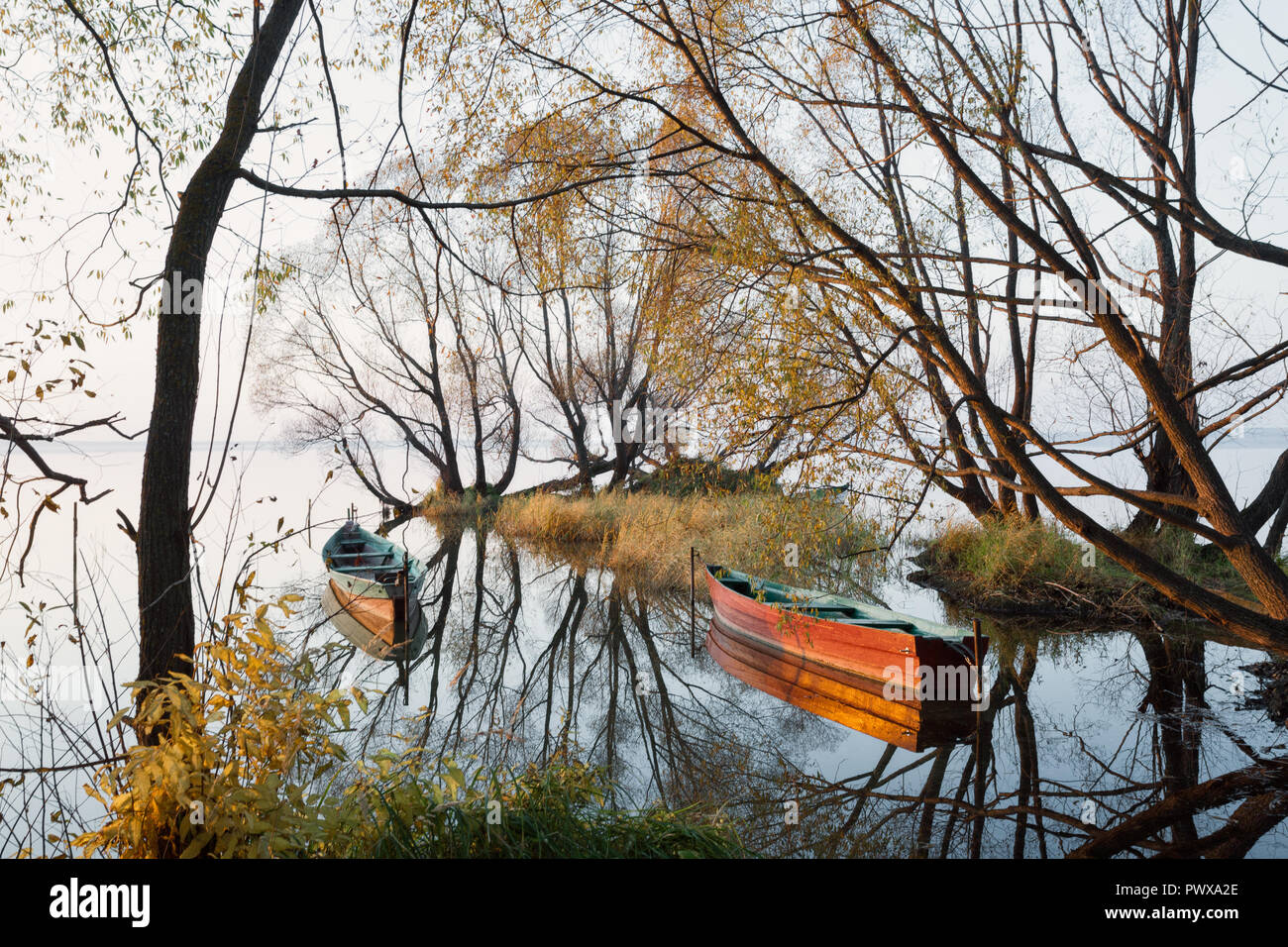 Fischerboote in einer ruhigen Bucht in einem leichten Nebel im Herbst Sonnenuntergang Stockfoto