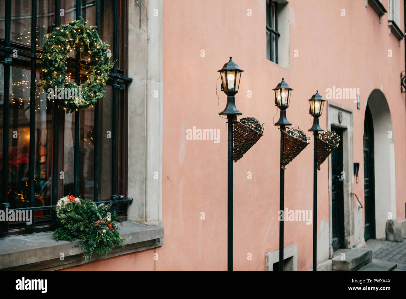 Weihnachtsschmuck des Gebäudes. Weihnachten Kränze auf dem Windows und verzierten Strassenlaternen mit Girlanden neben der traditionellen Europäischen Gebäude in Warschau. Stockfoto