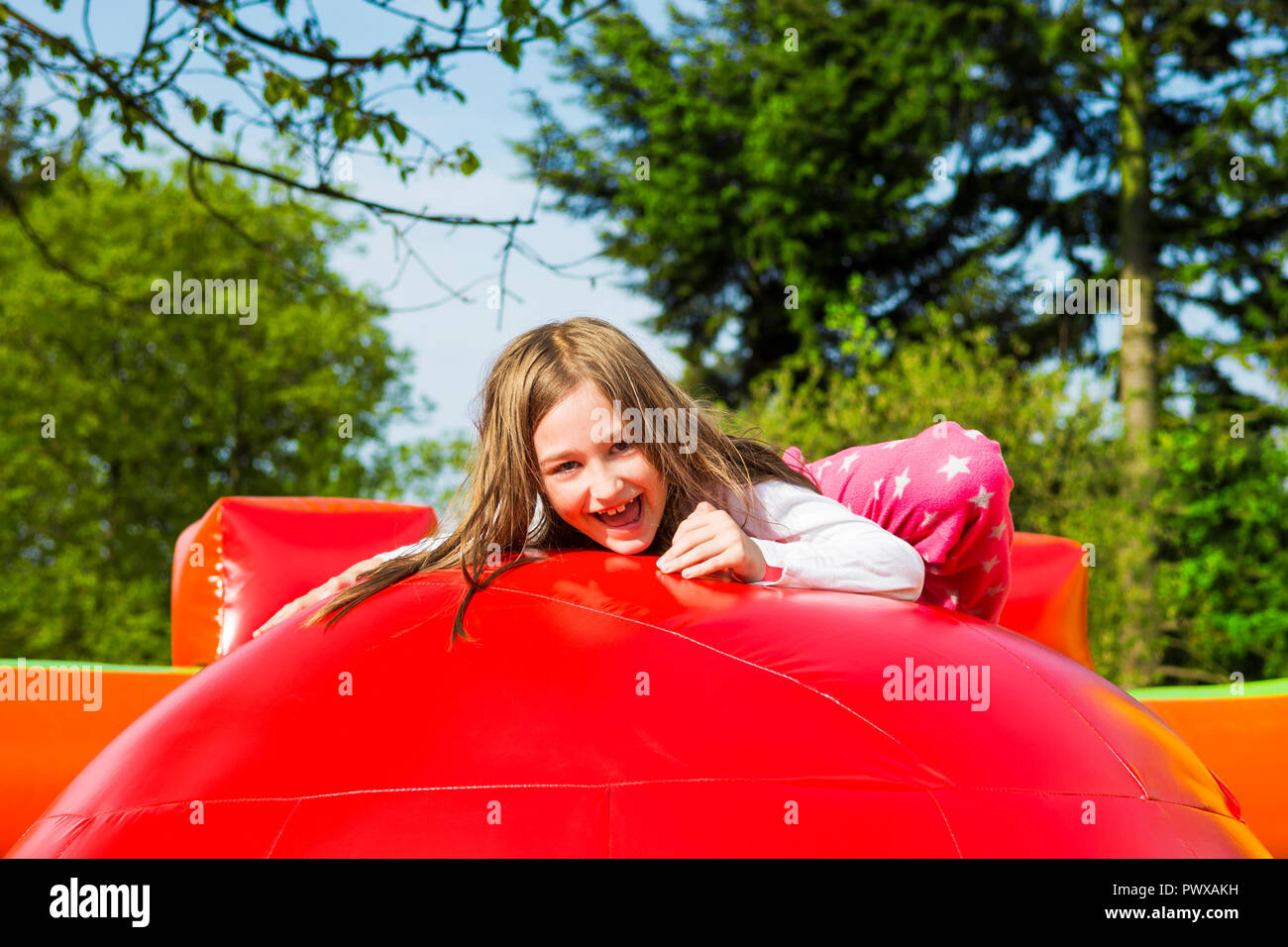 Gerne kleine Mädchen haben viel Spaß auf einem Aufpumpen schloss beim Springen auf der großen Kugeln. Stockfoto