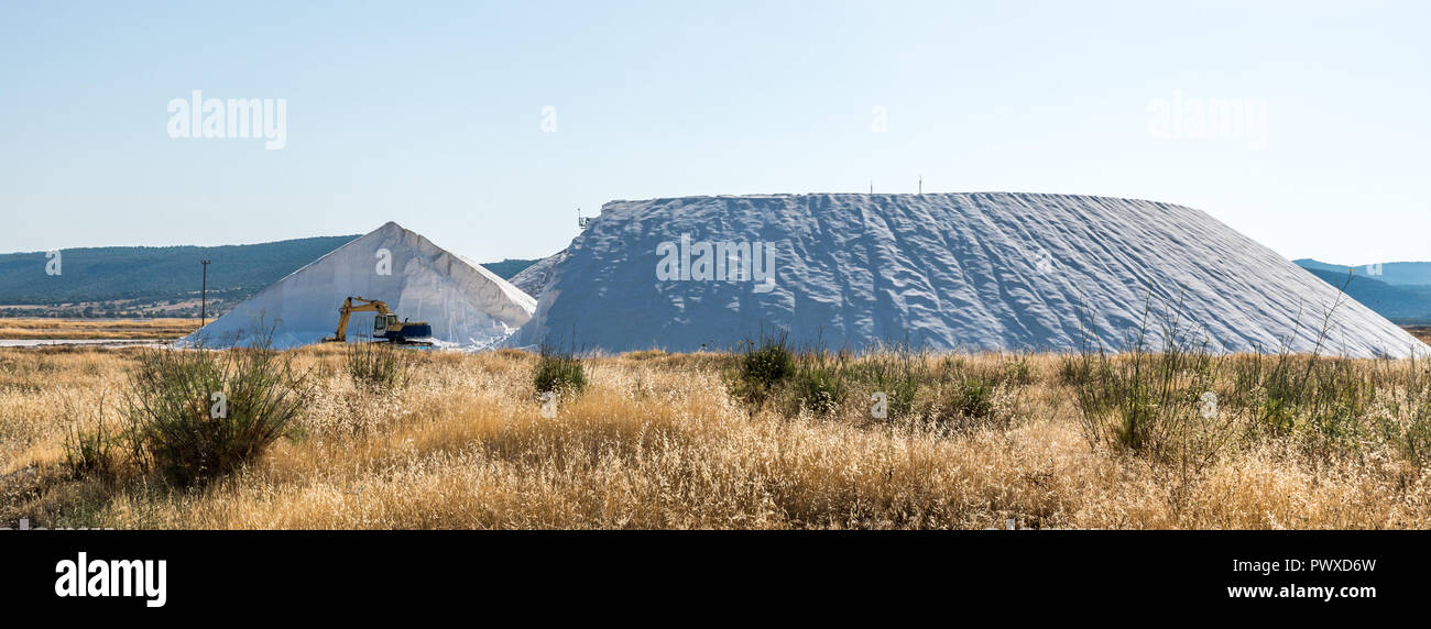 Bagger Maschinen vor zwei große Berge von Salz Stockfoto