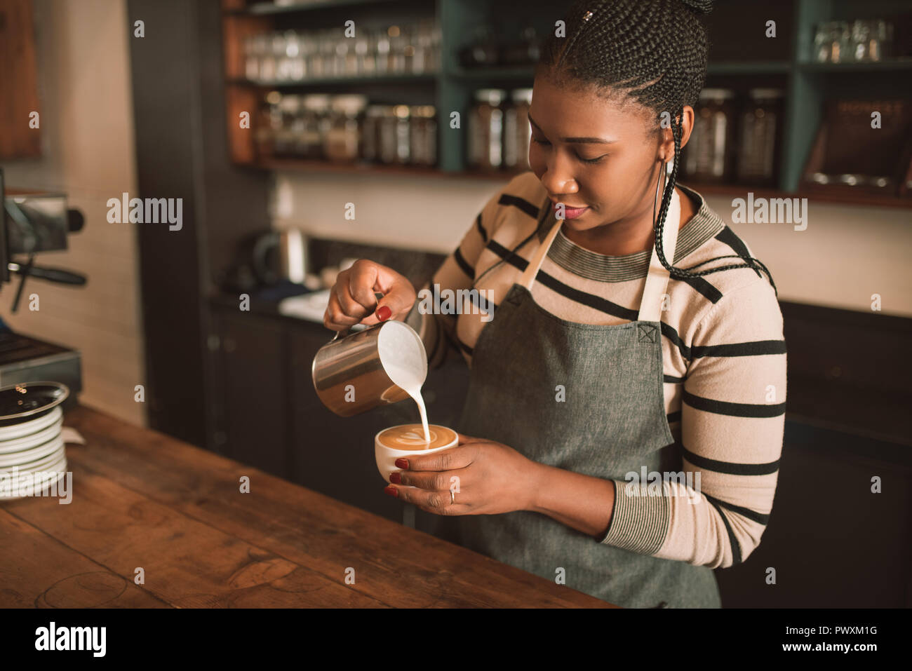 Lächelnden jungen afrikanischen Barista, eine frische Tasse Cappuccino Stockfoto