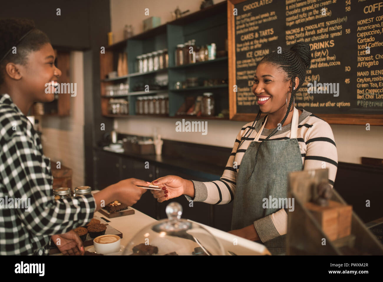Lächelnde Frau ihre Kreditkarte in ein Cafe Barista Stockfoto
