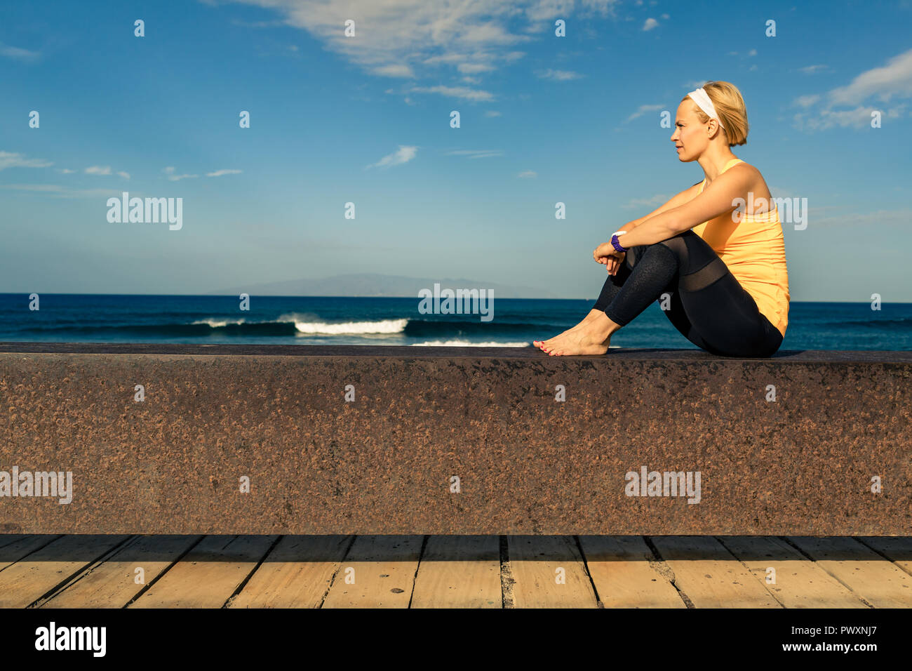 Frau meditieren yoga Pose, Blick aufs Meer, den Strand und die hölzernen Gehweg. Motivation und inspirierenden Sommer Meer Landschaft. Gesunder Lebensstil im Freien in Stockfoto
