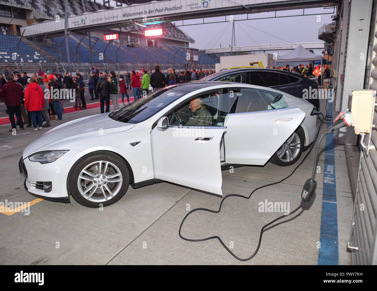 Klettwitz, Deutschland. Okt, 2018 18. Ein Tesla Elektroauto wird auf dem Lausitzring während der#WelcomeTesla Kampagne berechnet. Während der Werbekampagne für ein Tesla batterie Fabrik in Brandenburg, Lausitzer sind Sie den Himmel mit Taschenlampen und Spotlights. Foto: Patrick Pleul/dpa-Zentralbild/dpa/Alamy leben Nachrichten Stockfoto