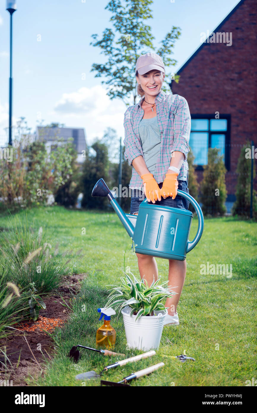 Junge strahlende Gärtner tragen Sie bequeme Kleidung holding Garten Sprinkler Stockfoto
