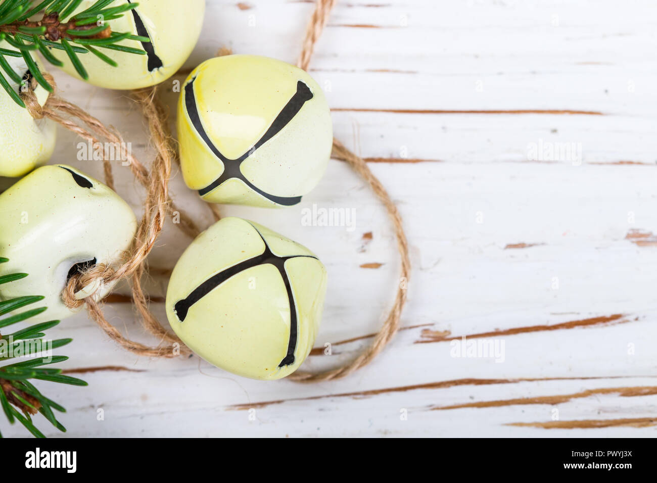 Weihnachten Dekoration - gelb Jingle bells auf dem alten weißen Tisch. Für das neue Jahr. Das Konzept der Feier. Im rustikalen Stil. Kopieren Sie Raum und selektive foc Stockfoto