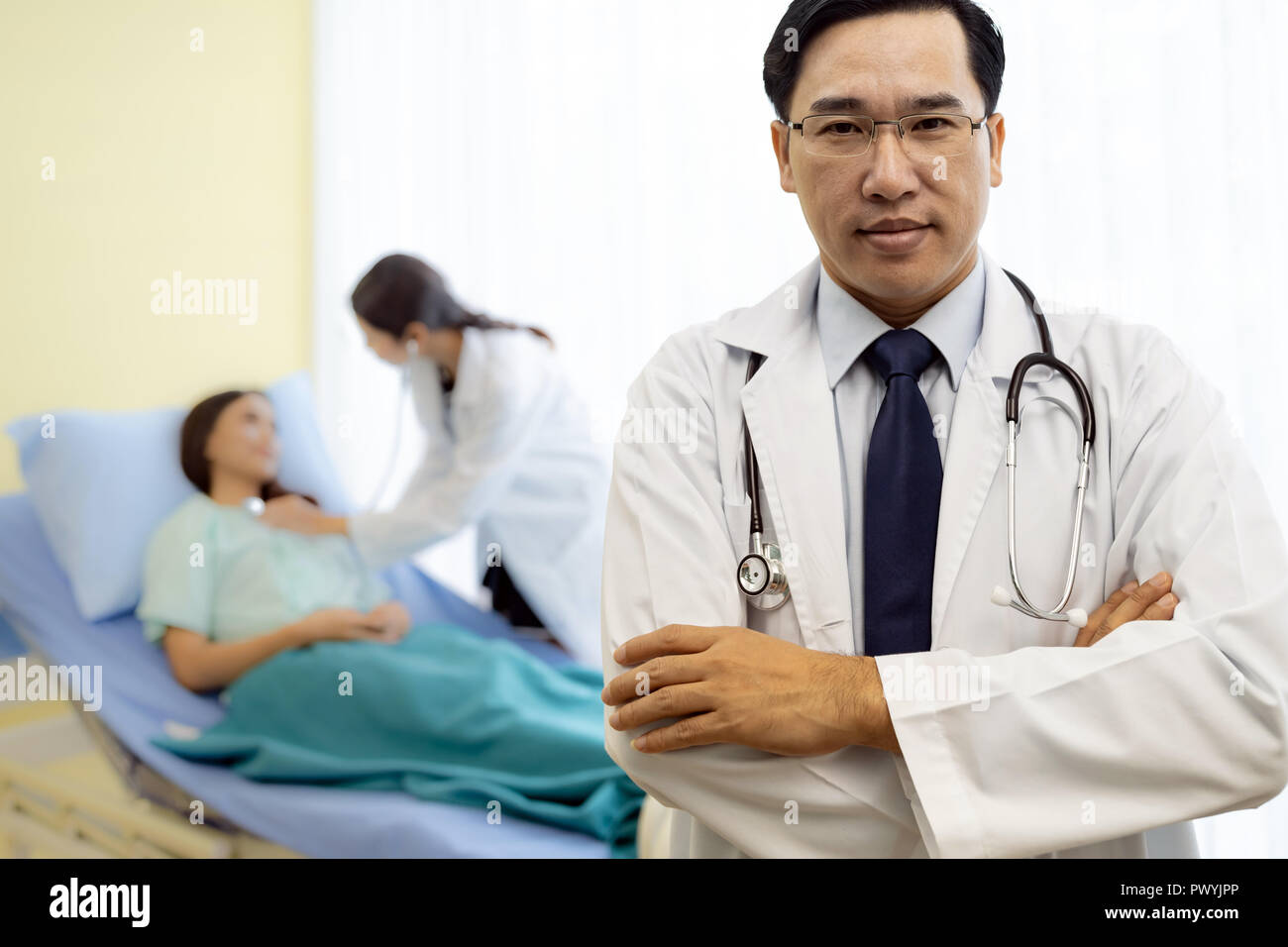 Portrait von jungen Erwachsenen Arzt mit Krankenschwester und Patient im Hintergrund. Stockfoto