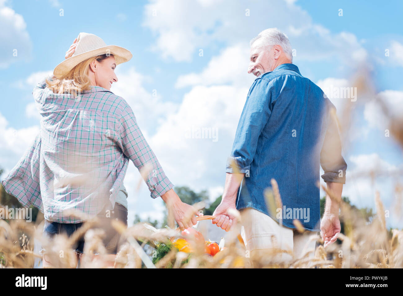 Blonde Frau an ihrem stattlichen Mann sucht nach dem Sammeln der Ernte Stockfoto