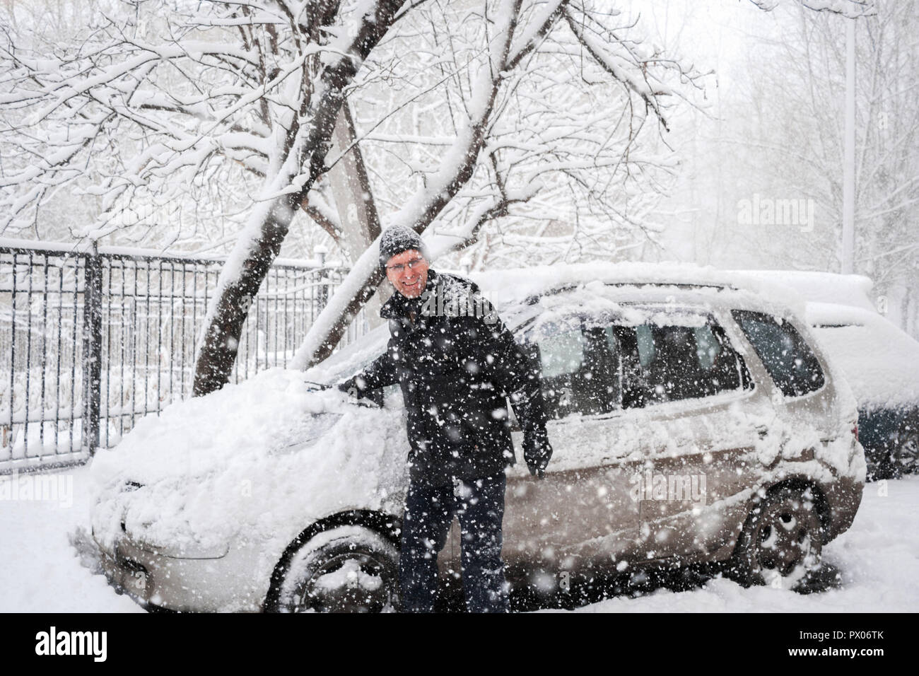 Freundlich lächelnden Mann putzt sein Auto und Kamera während starker Schneefall. Winter rauhes Wetter. Stockfoto