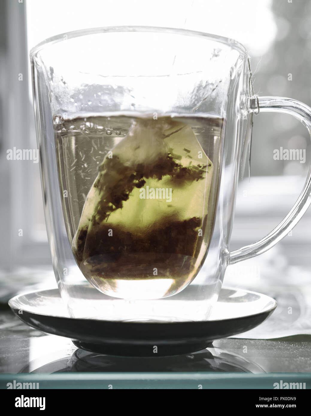 Ein klares Glas Schale mit hellen Kaffee und Teebeutel. Stockfoto