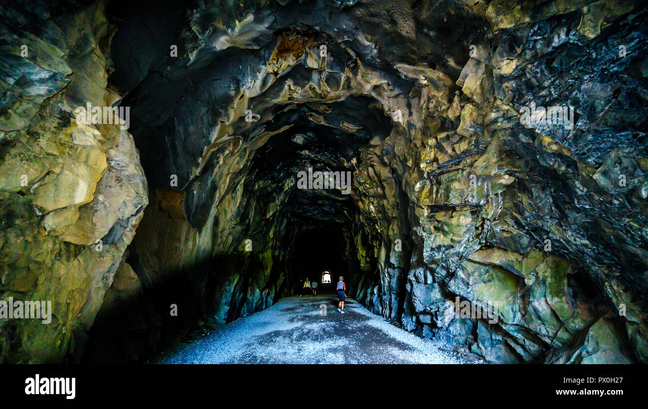 Touristen zu Fuß in den Othello Tunnels, die über den Coquihalla Canyon für die an den inzwischen aufgegebenen Kettle Valley Railway an der Hoffnung, BC, Kanada geschnitzt wurden, Stockfoto