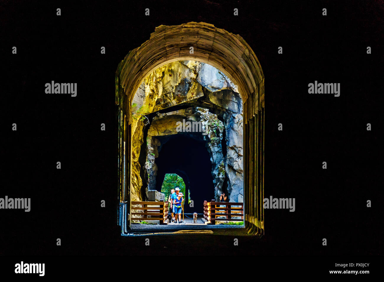 Touristen zu Fuß in den Othello Tunnels, die über den Coquihalla Canyon für die an den inzwischen aufgegebenen Kettle Valley Railway an der Hoffnung, BC, Kanada geschnitzt wurden, Stockfoto