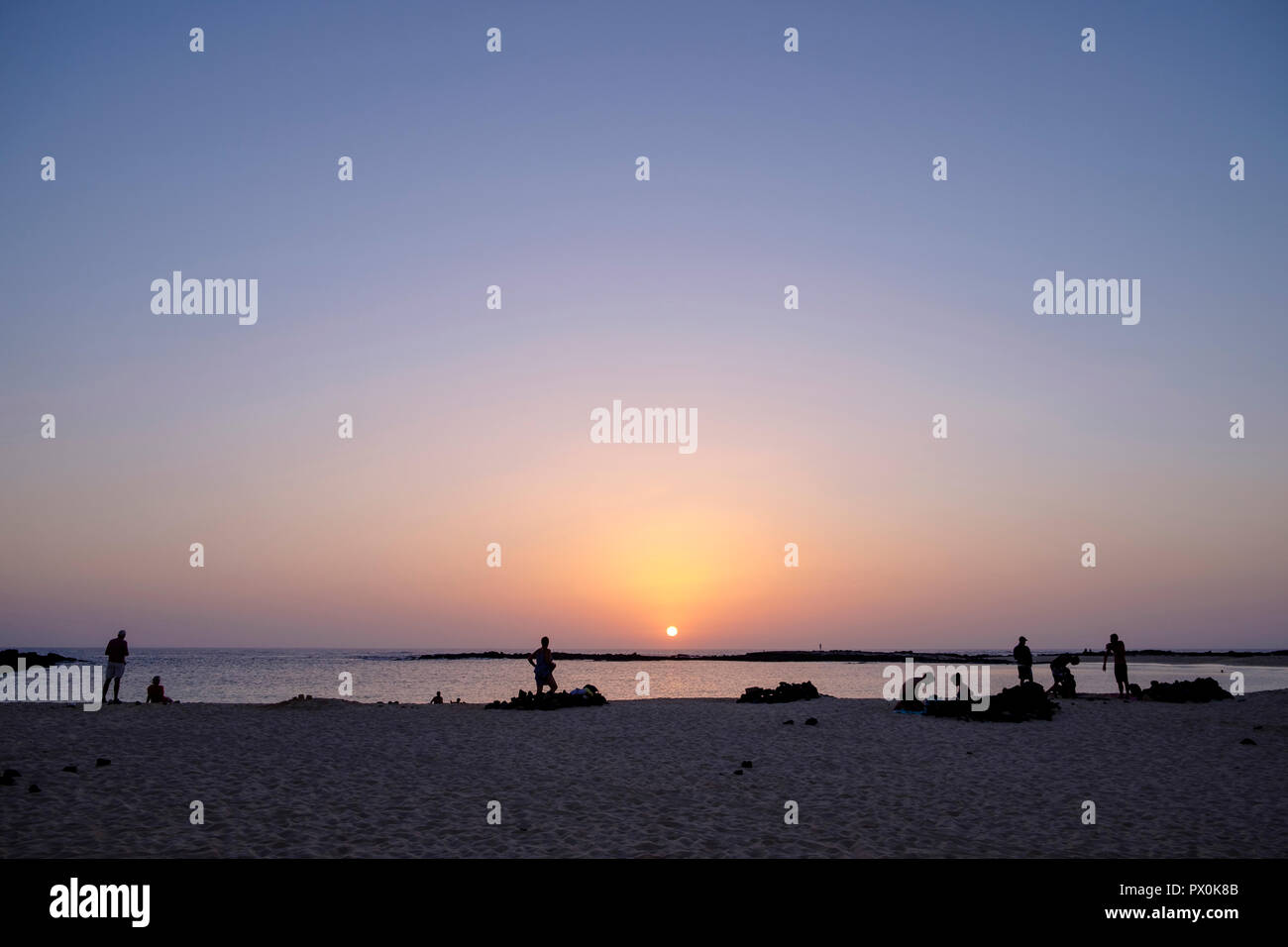 Menschen beobachten Sie den Sonnenuntergang vom Strand Playa Chica in der Nähe von El Cotillo, Fuerteventura. Stockfoto