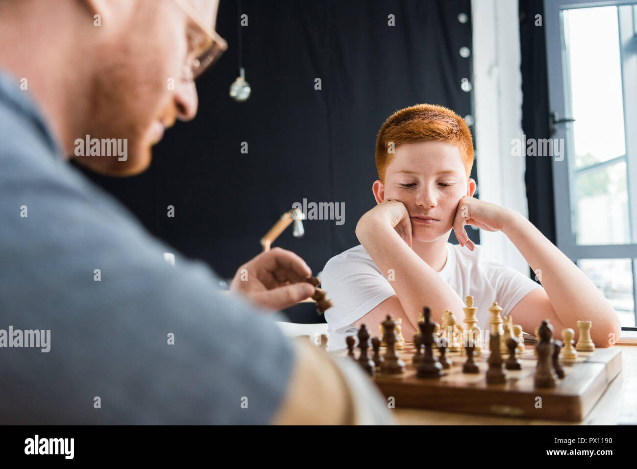 Nachdenklich Sohn gesucht am Schachbrett zu Hause Stockfoto