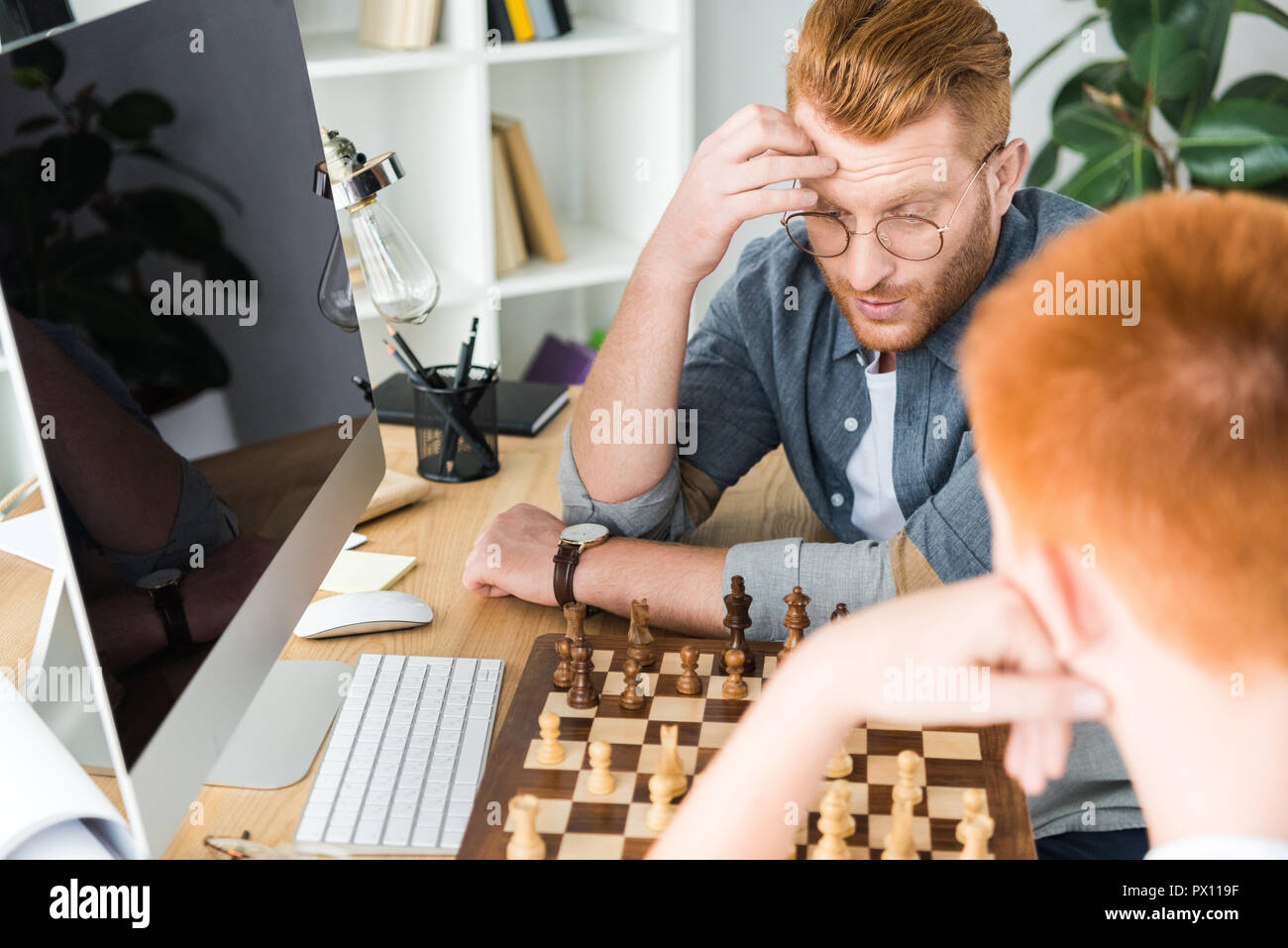 Nachdenklich, rote Haare Vater und Sohn Schach spielen zu Hause Stockfoto