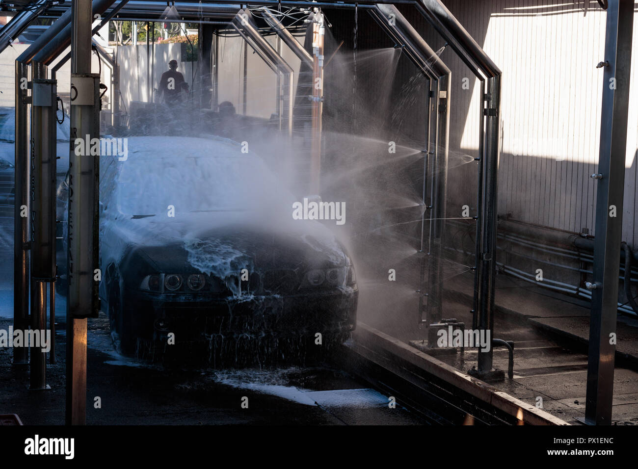 Auto Spray in einem automatisierten Autowaschanlage gewaschen, Auto, Spray in einem automatisierten Autowaschanlage gewaschen, Arbeiter im Hintergrund Stockfoto