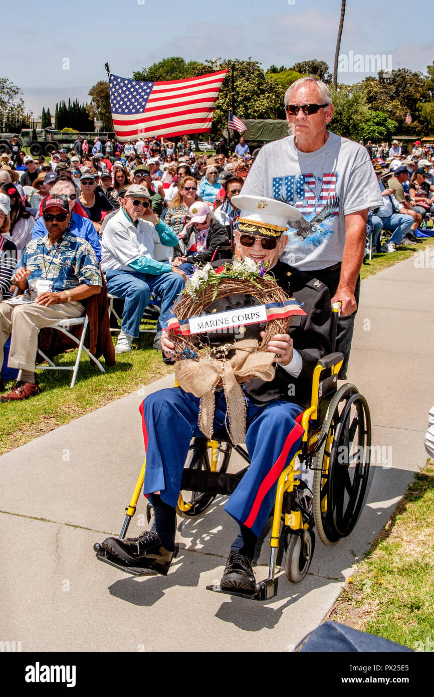 Eine ältere US Marine Veteran im Rollstuhl trägt einen Kranz während des Memorial Day Zeremonien bei einer Costa Mesa, CA, Friedhof. Stockfoto