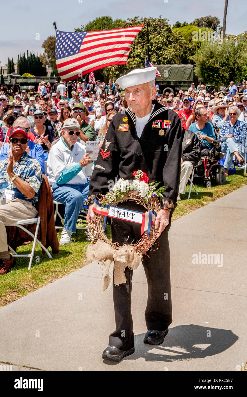 Eine ältere US Marine Veteran im Rollstuhl trägt einen Kranz während des Memorial Day Zeremonien bei einer Costa Mesa, CA, Friedhof. Stockfoto