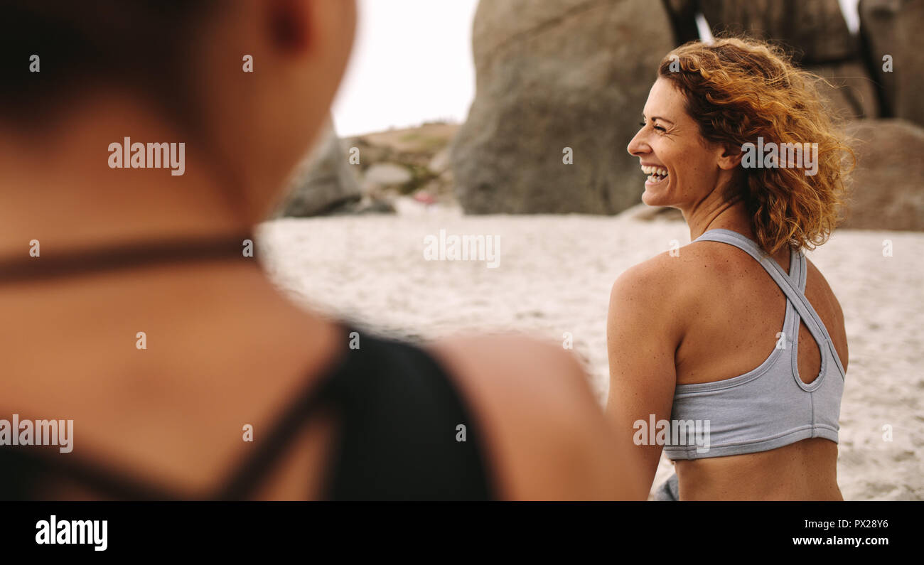 Frauen Yoga sitzen am Strand. Ansicht der Rückseite des glücklichen Frauen in Fitness Kleidung am Strand. Stockfoto