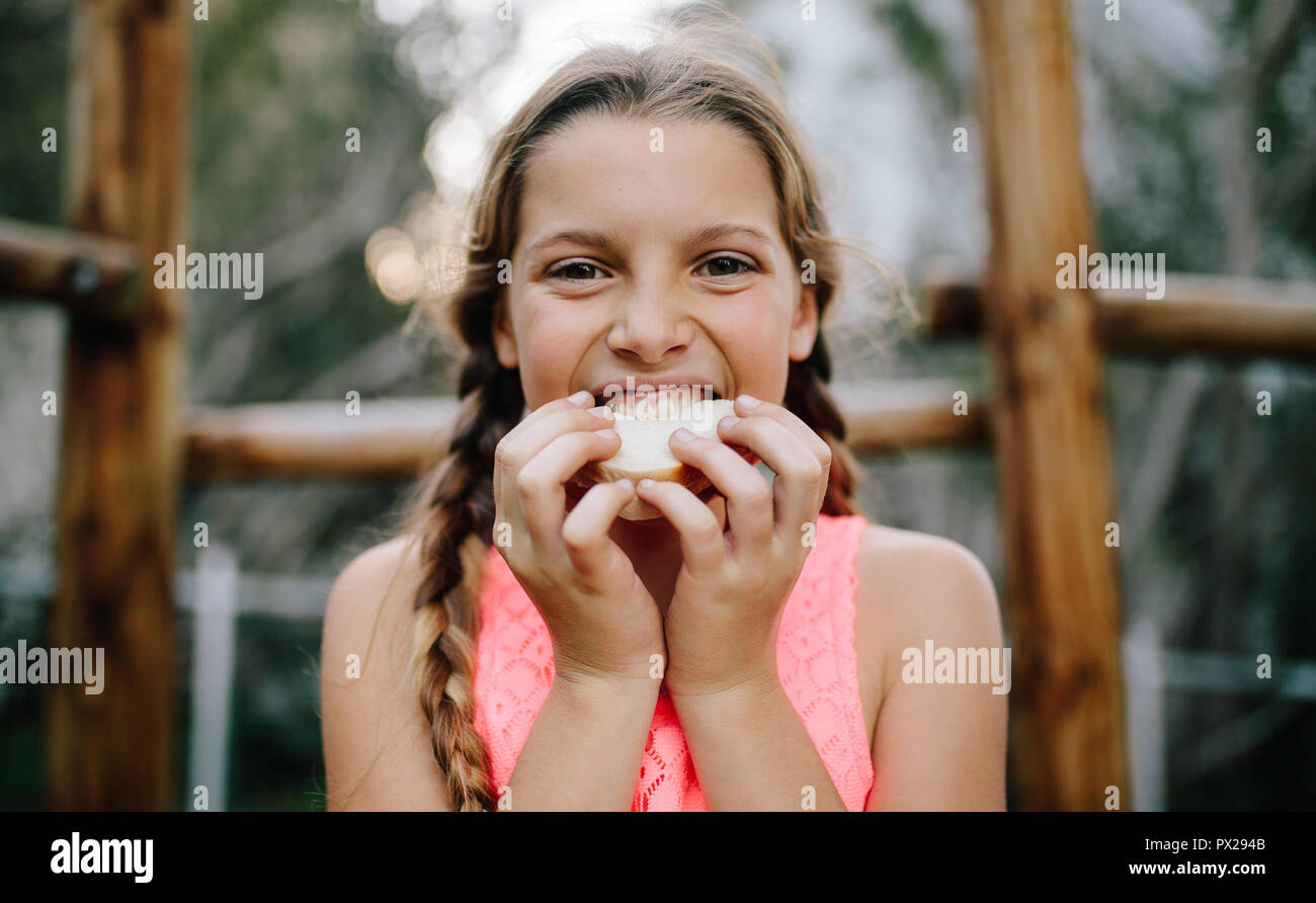 Porträt eines Mädchens, das Essen das Essen bei einem Picknick im Freien. Nahaufnahme von einem Mädchen beißen ein Sandwich stehen im Freien. Stockfoto