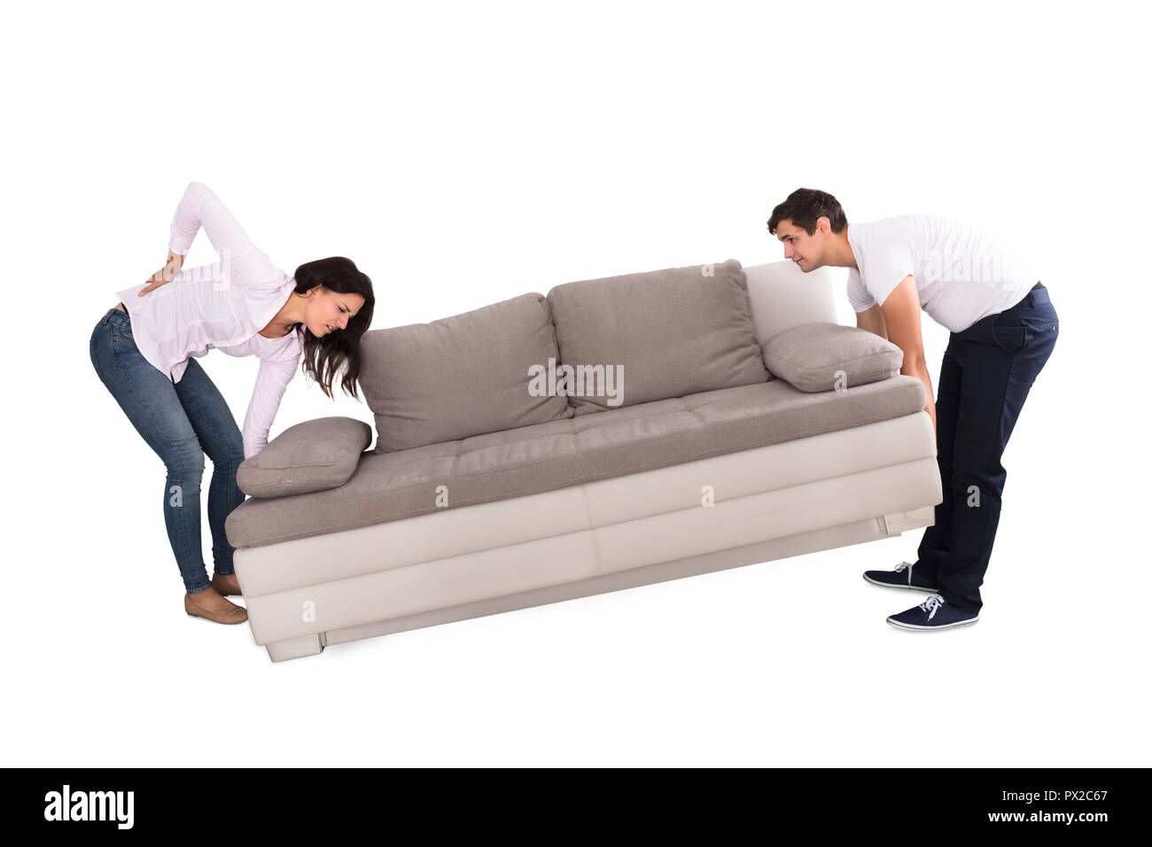 Junge Frau mit Rückenbeschwerden beim Anheben Sofa mit ihrem Ehemann auf weißem Hintergrund Stockfoto