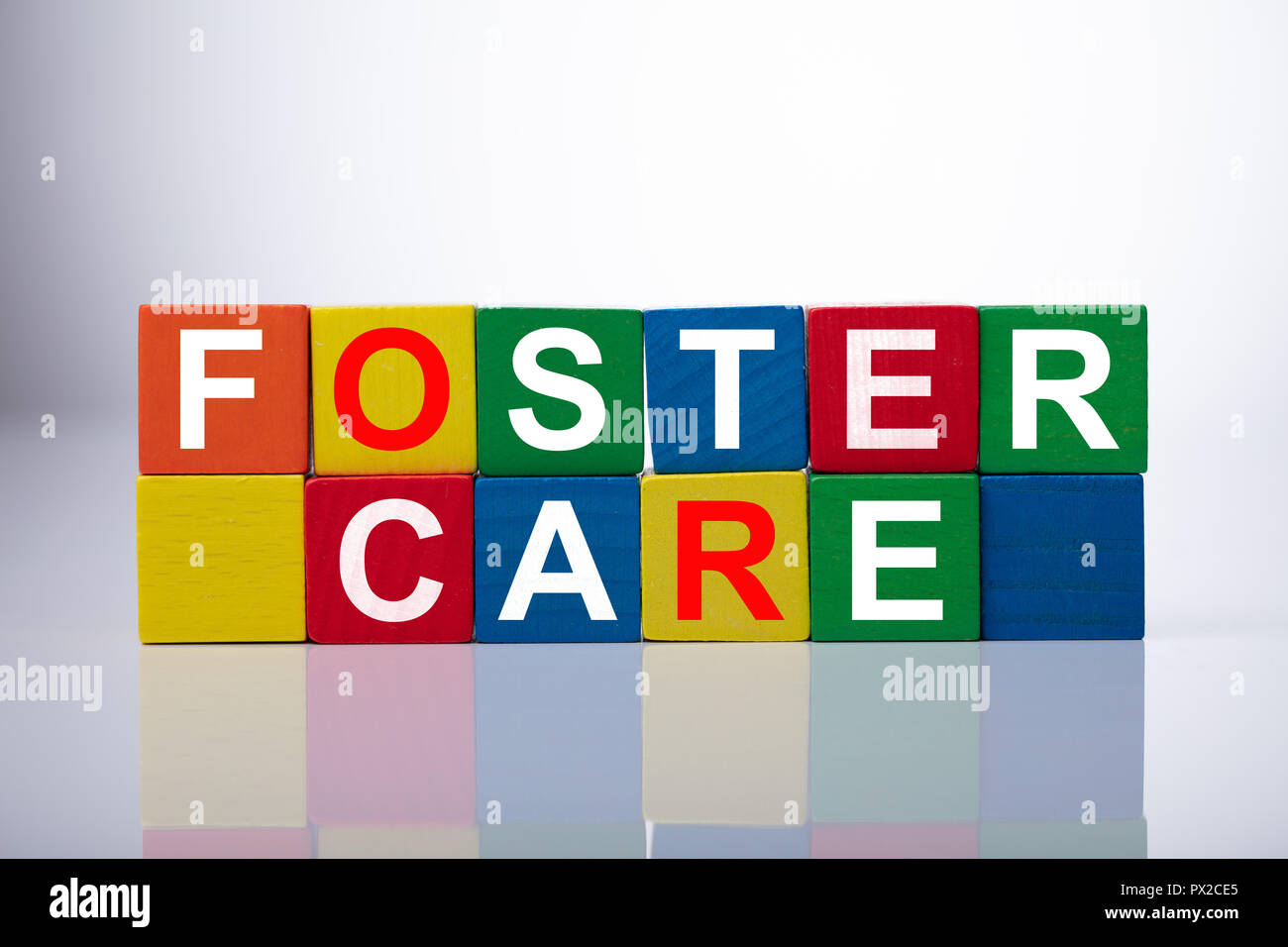 In der Nähe von Foster Care würfelförmige Blöcke auf reflektierenden Hintergrund Stockfoto