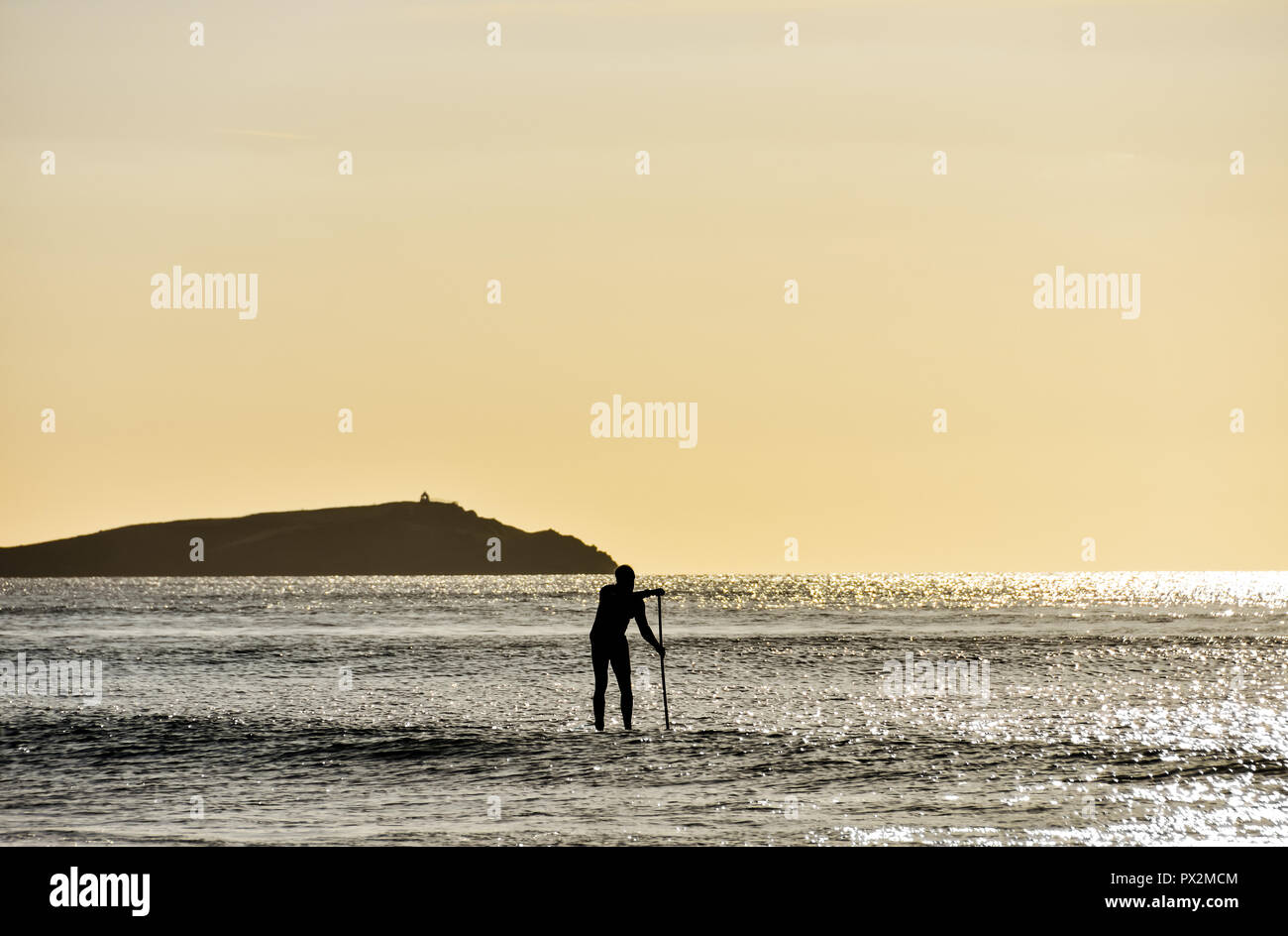 Newquay, Cornwall, England. September 2018. Ein männlicher paddleboarding über Watergate Bay Beach an einem sonnigen Nachmittag im Herbst Stockfoto