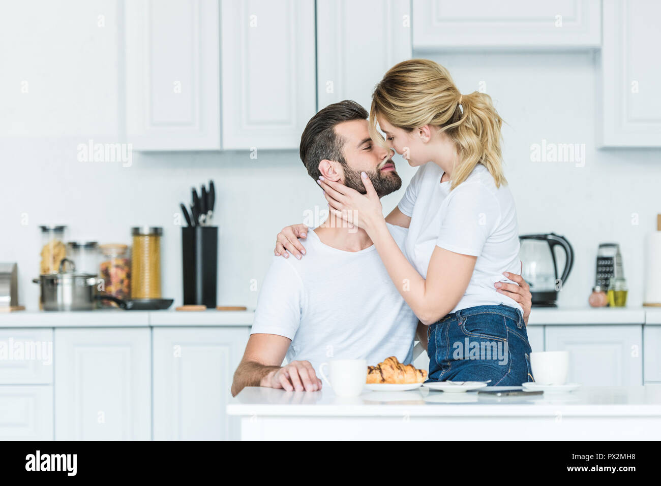 Schönes glückliches junges Paar in Liebe küssen beim Frühstück in der Küche  Stockfotografie - Alamy