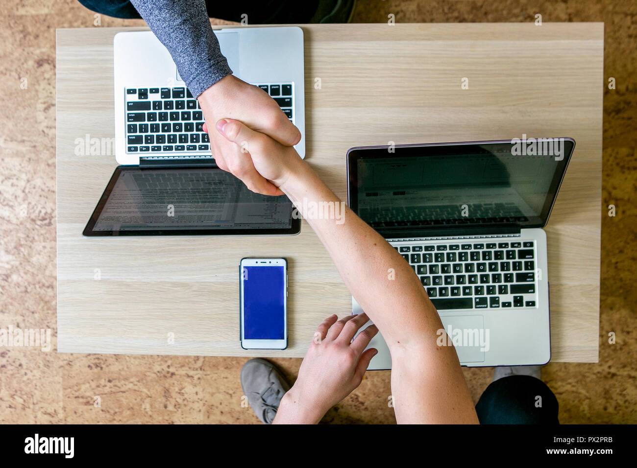 Zwei junge Menschen, die auf den Laptops im Büro. Am Tisch sitzen einander gegenüber, Handshake, Ansicht von oben, close-up Stockfoto