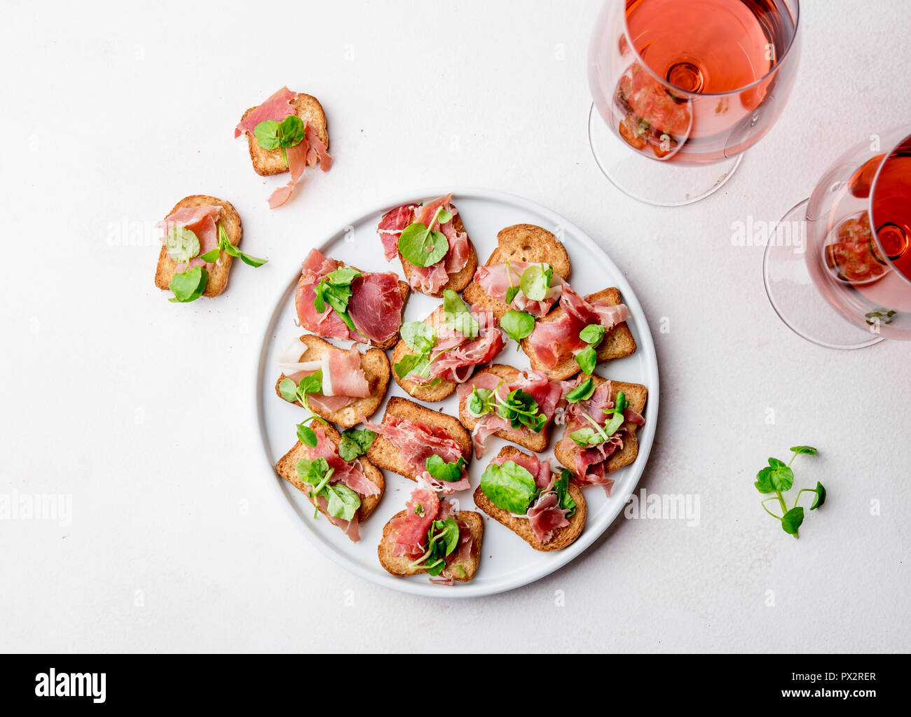 Mini offene Sandwiches mit Jamon Serrano auf weiße Platte und Rose Wein. Stockfoto