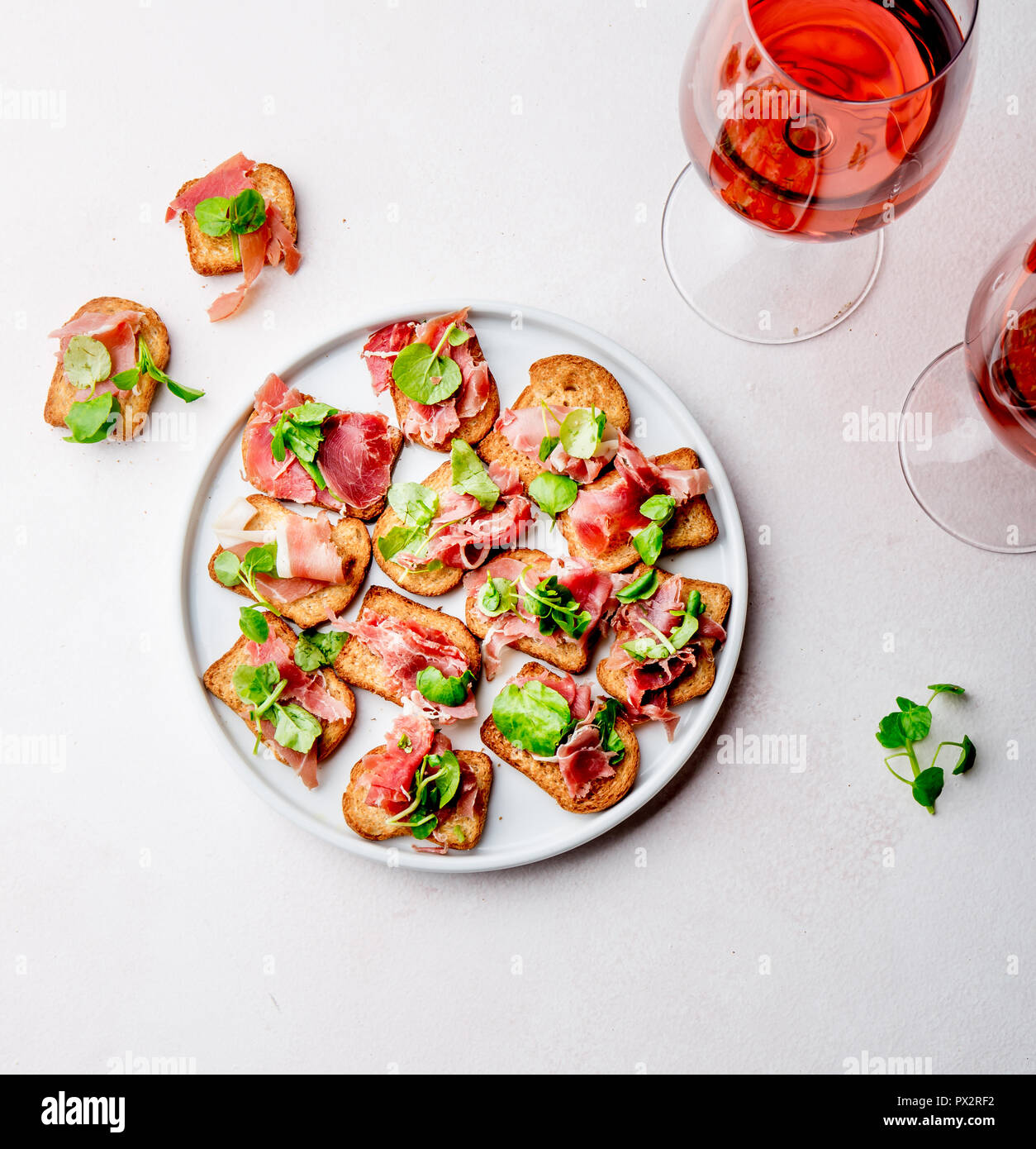 Mini offene Sandwiches mit Jamon Serrano auf weiße Platte und Rose Wein. Stockfoto
