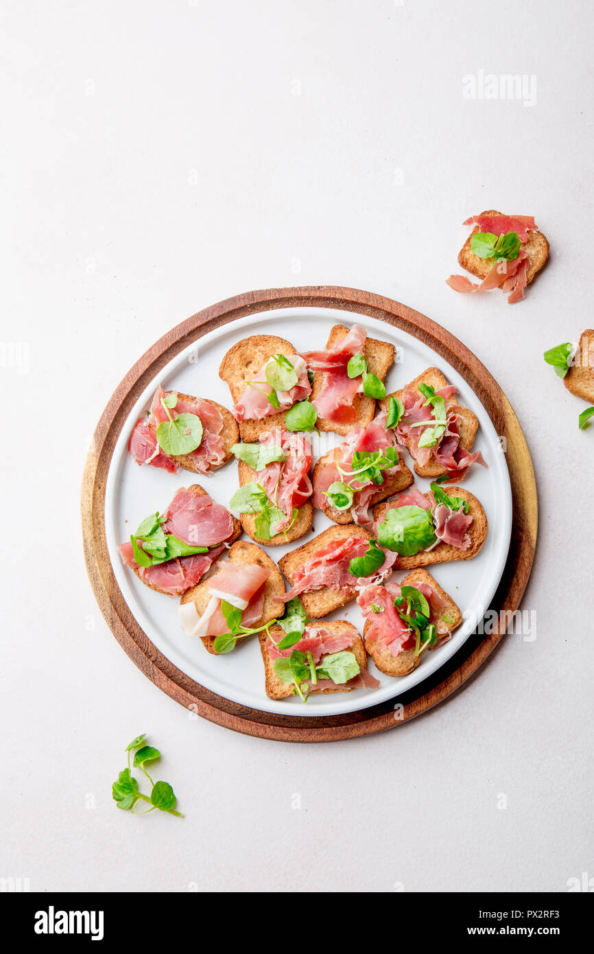 Mini offene Sandwiches mit Jamon Serrano auf weiße Platte. Stockfoto