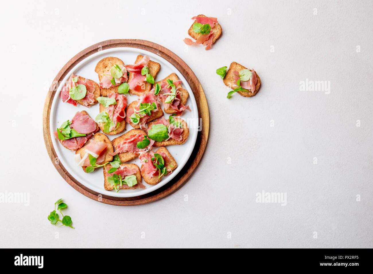 Mini offene Sandwiches mit Jamon Serrano auf weiße Platte. Stockfoto