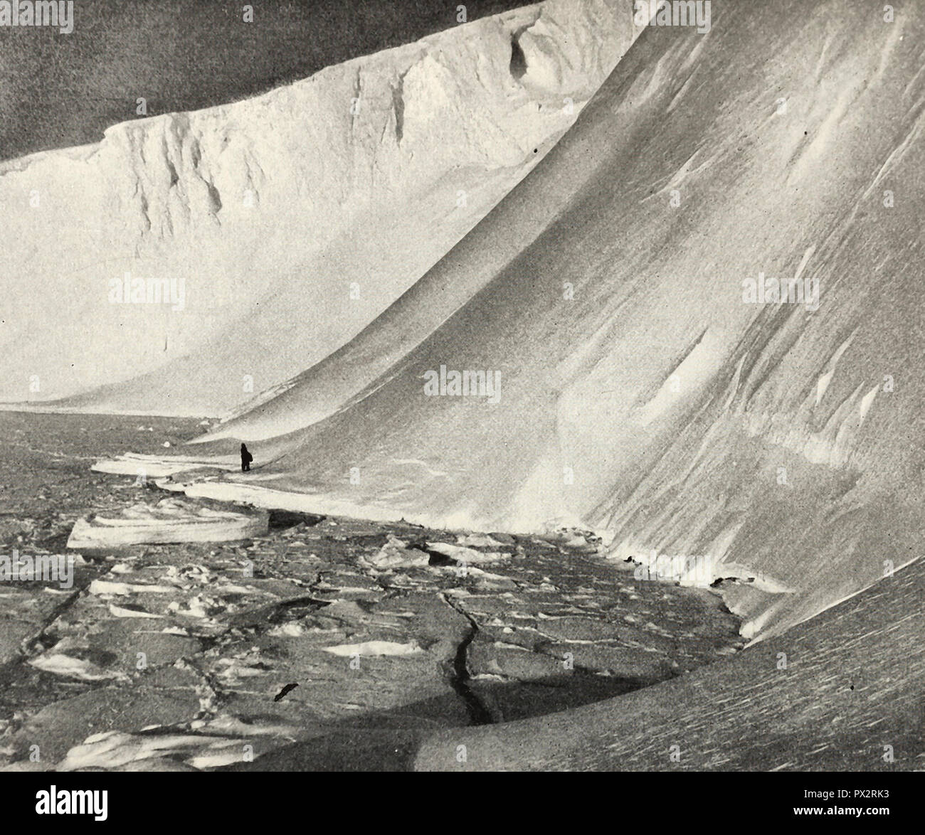 Menschen mit Furcht erfüllt, wie er steht unter gewaltigen Eiswände, der Turm 180 Meter über ihm, Antarktis, um 1910 Stockfoto