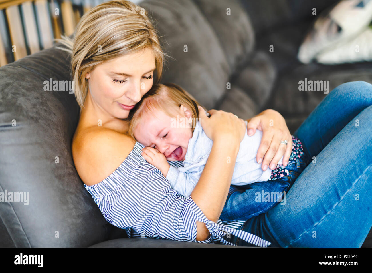 Junge Mutter mit Baby auf dem Sofa zu Hause, mein Kind weint Stockfoto