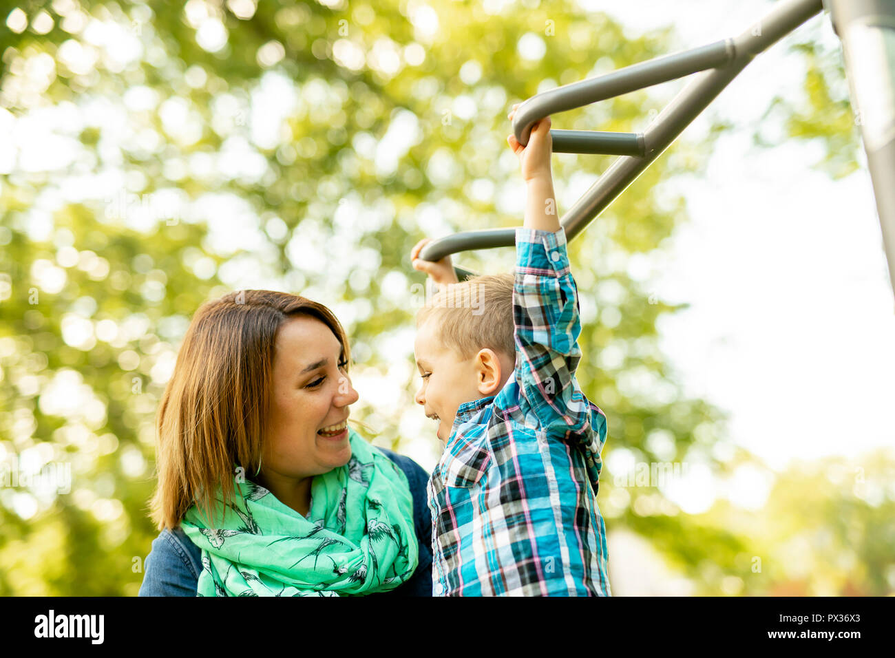 Eine entzückende kleine Junge seine Zeit in einem Spielplatz Struktur mit Mutter Stockfoto