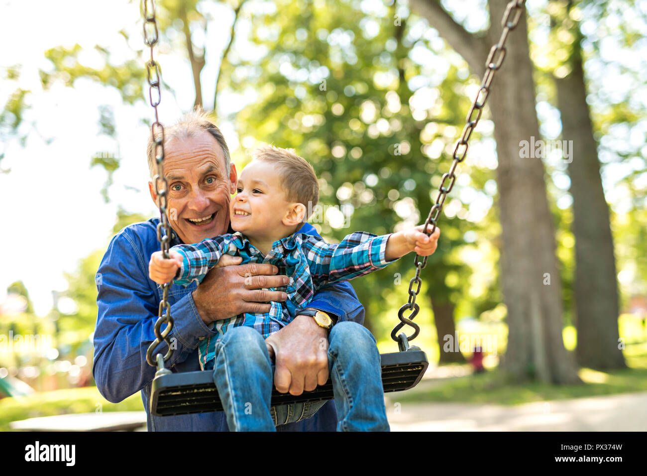 Ein Großvater seinem Enkel auf der Schaukel drücken Stockfoto