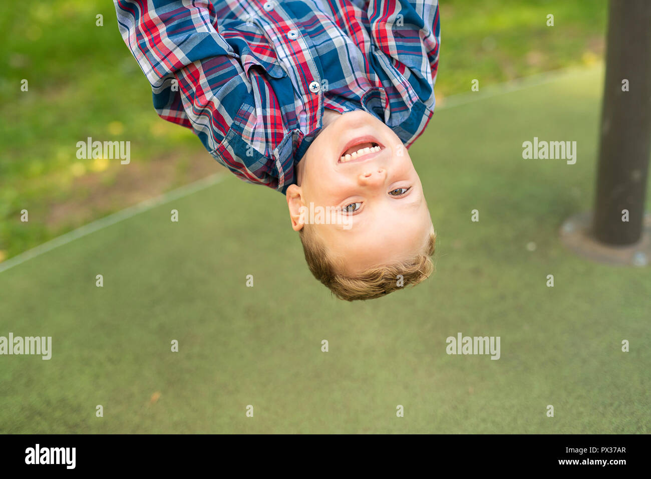 Eine nette junge kopfüber auf einem Spielplatz Stockfoto
