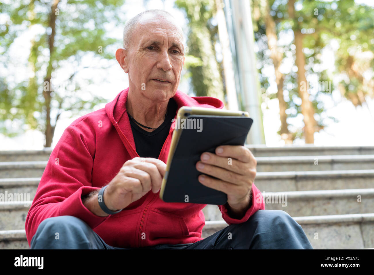 Kahlen älterer Mann mit digitalen Tablet beim Sitzen auf der stairc Stockfoto